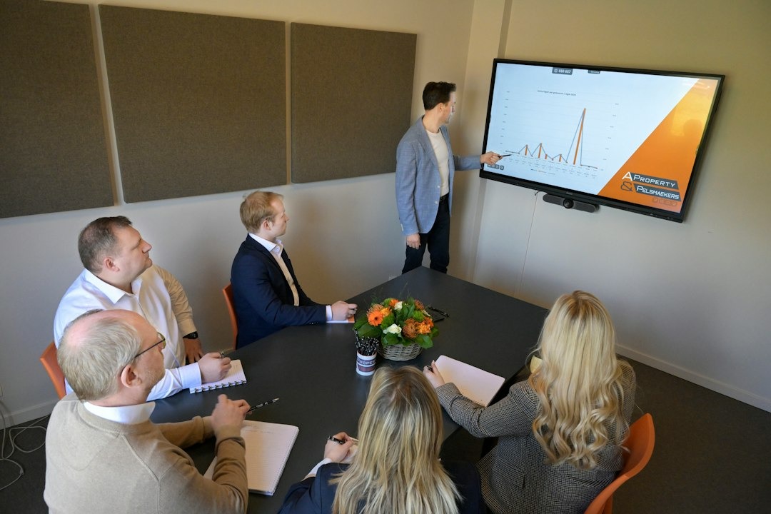 Professionals in a meeting presenting data on a large screen.